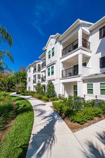 a sidewalk in front of some apartments with grass and trees